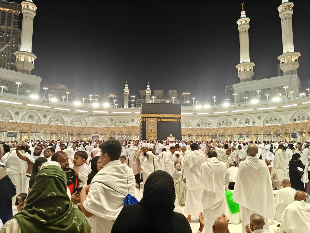 Night view of pilgrims gathered around the Kaaba in Mecca, Saudi Arabia during Hajj.